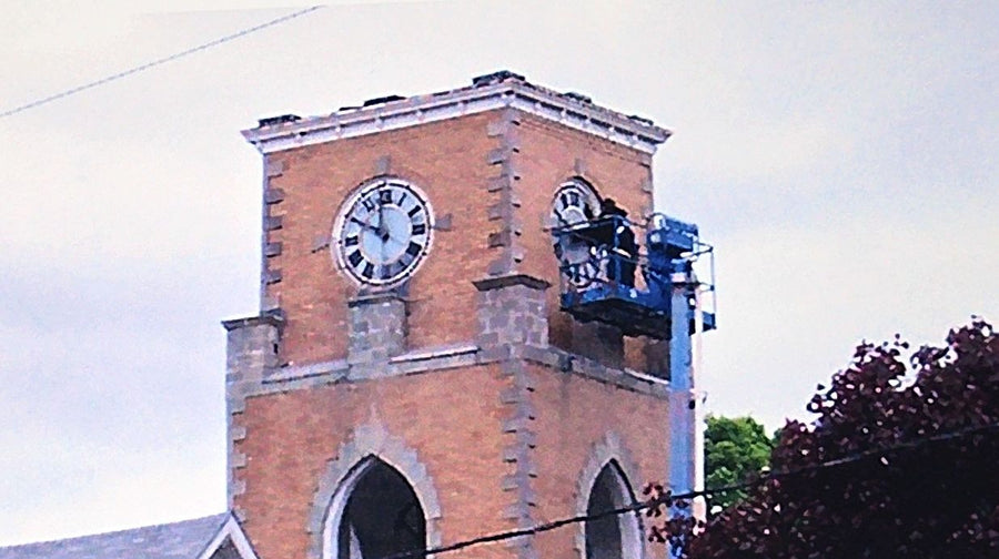 The crew on a cherry picker as the clock faces come off