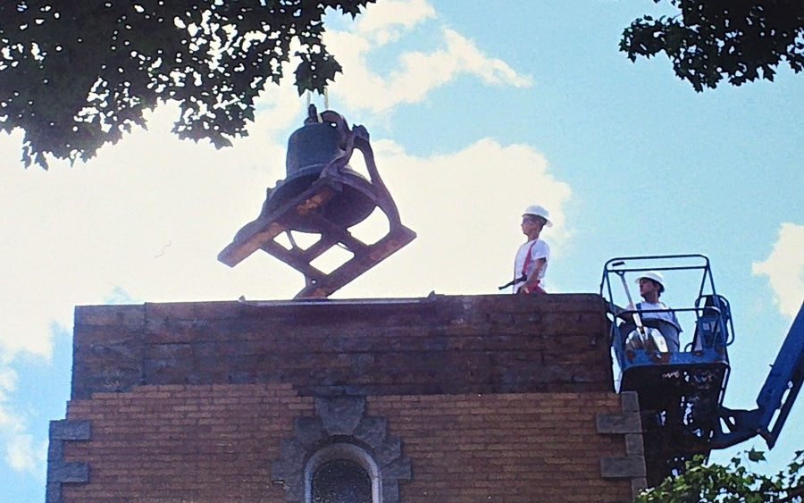 The bell lifted out as a worker looks on from the cherry picker